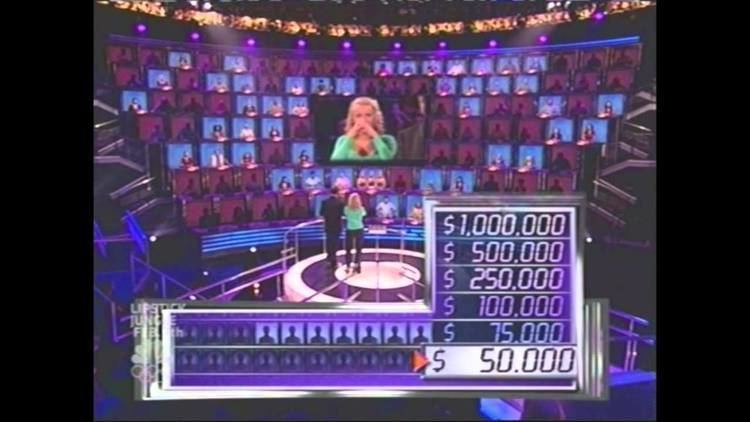 In a movie scene of 1 vs. 100 (Philippine game show) 2008, in the game show room with a large stage for contestant and the audience who is sitting at the back showing only their silhouette, in front is a digital bar with silhouette of people, and the prize money from 50,000, 75,000, 100,000, 250,000, 500,000, 1,000,000, from left is the host, with his back view, has black hair wearing a black suit and black pants, at his right is the contestant has a blonde hair wearing a green long sleeve and a black pants,