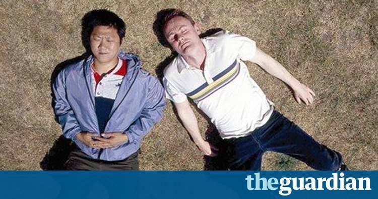 Sean Lock and Benedict Wong lying on the ground in a scene from the 2002 sitcom 15 Storeys High