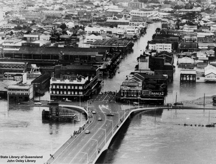 An aerial photograph showing the buildings and thousands of homes are swamped in floodwaters and also showing the remains of the bridge after the floods in the devastating 1974 Brisbane floods.