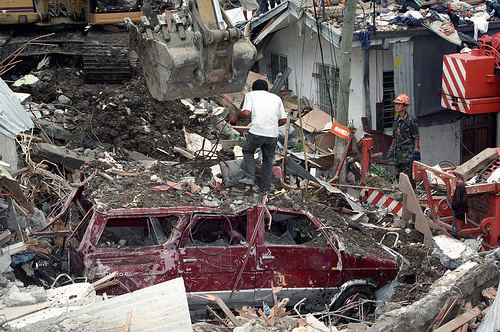 Effects of 1999 Cherry Hill Subdivision landslide are houses and cars were covered with soil and people helping in search and rescue operations.