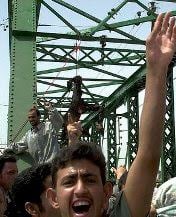 Jubilant Iraqis posing with the charred corpses