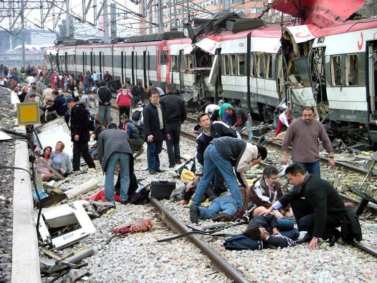 Some people are lying on the ground and others are helping people with injuries in the 2004 Madrid train bombings