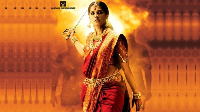 Anushka Shetty holding a sword with fire at her back and wearing a gold and red dress in the 2009 horror fantasy film, Arundhati