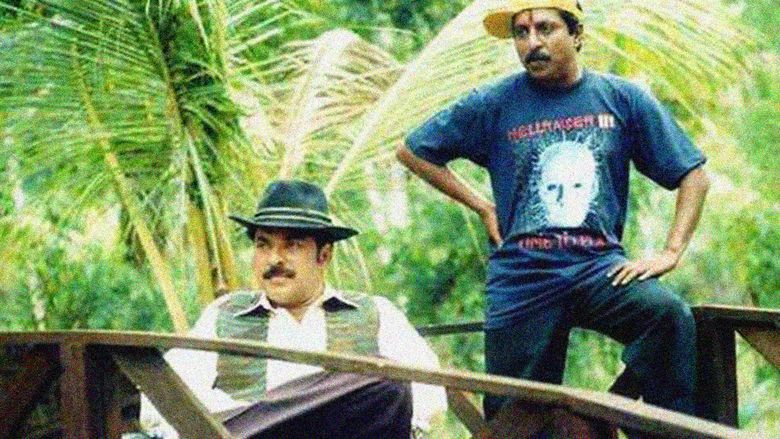 Mammootty sitting on the chair and looking afar while Sreenivasan leaning on the guard rail in a scene from the 1996 film, Azhakiya Ravanan