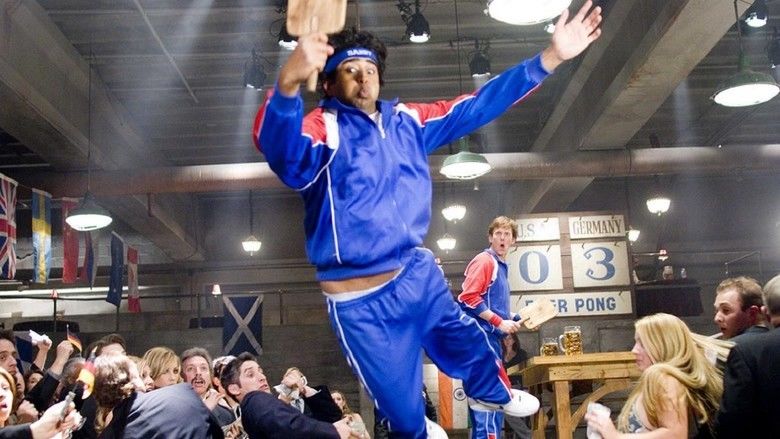 Jay Chandrasekhar jumping while wearing a red and blue jacket and track pants in a movie scene from the 2006 film Beerfest