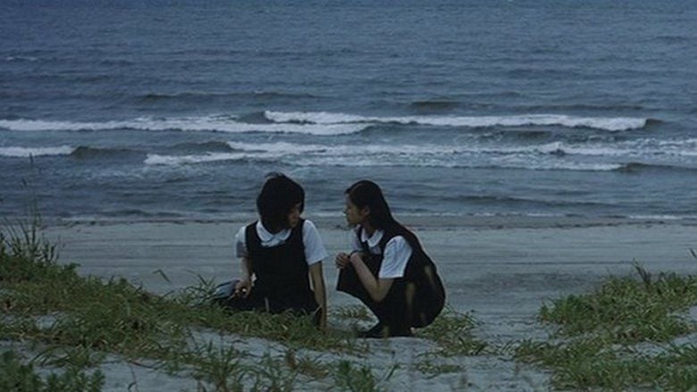 Mikako Ichikawa	as Kayako Kirishima and Manami Konishi as Masami Endo talking with each other on a beach and wearing their school uniforms in a scene from Blue, a 2002 Japanese romantic drama.