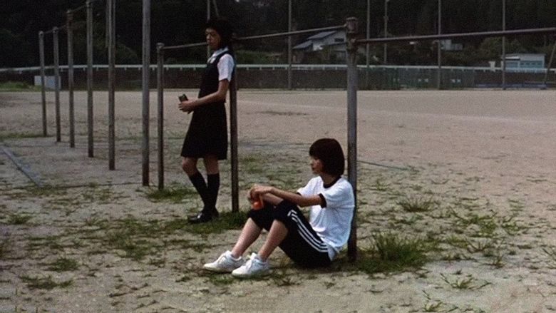 Mikako Ichikawa	as Kayako Kirishima and Manami Konishi as Masami Endo with serious faces while at the school playground and wearing their school uniforms in a scene from Blue, a 2002 Japanese romantic drama.
