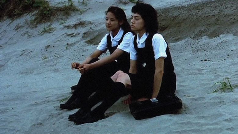 Mikako Ichikawa	as Kayako Kirishima and Manami Konishi as Masami Endo with serious faces while on a beach and wearing their school uniforms in a scene from Blue, a 2002 Japanese romantic drama.