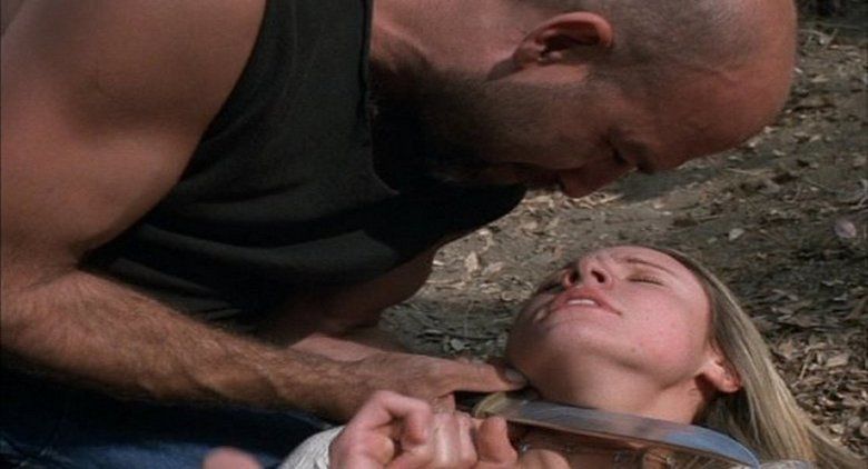 Maya Barovich as Angelica struggling with her eyes closed and lying on the ground while Kevin Cage as Chaos puts a knife on her neck in a scene from the movie "Chaos" (2005 film)