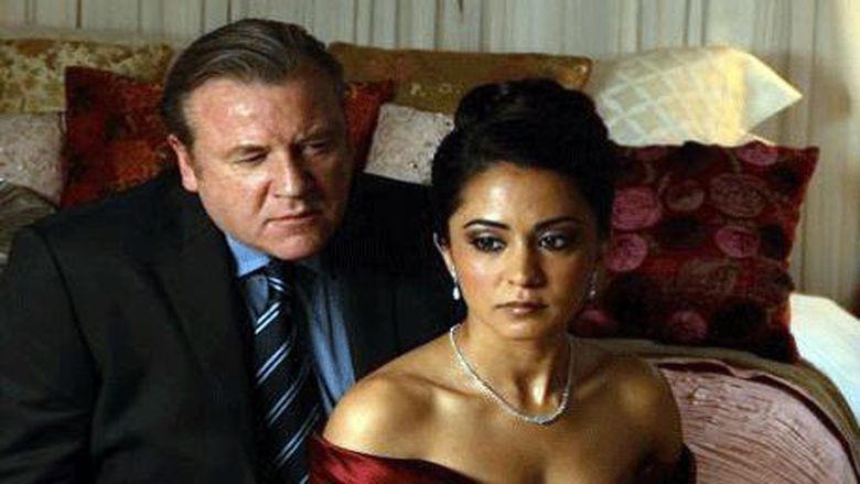 Ray Winstone looking at Parminder Nagra while they are sitting on the bed in a movie scene from the 2009 film Compulsion