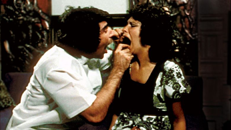 Harry Reems looking at Linda Boreman's mouth in a scene from the 1972 American pornographic film, Deep Throat. Harry is wearing a white polo and Linda is wearing a black and white floral blouse