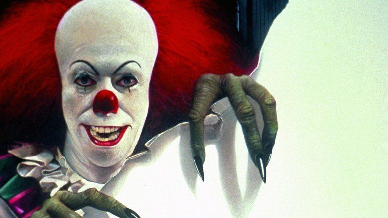 Tim Curry as Pennywise holding a torn white paper in the 1990 psychological horror drama miniseries, It