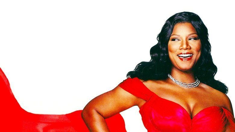 The movie poster of Last Holiday (2006 film), on a white background Queen Latifah is happy, standing with her hands on her waist, she has long black curly hair, wearing a silver necklace and a red long dress,