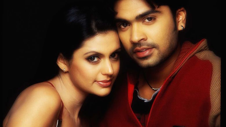 Mandira Bedi and Silambarasan are smiling while Mandira is wearing a red top and Silambarasan is wearing a red jacket in the 2004 Tamil crime thriller film, Manmadhan