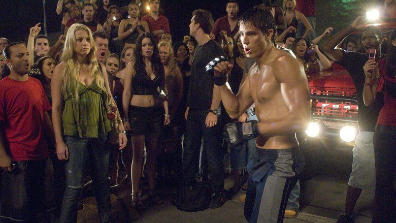 Amber Heard (front left) is looking at Sean Faris (middle front) and Lauren Leech beside Amber with a crowd in the background shouting and raising their hand beside a red car in a scene of the 2008 American martial arts film “Never Back Down”. Amber has long curly blonde hair, wearing a sling bag, bracelet, and a green spaghetti top and denim jeans, Lauren has black hair, wearing black hills, a black droptop, and a black shorts and Sean is doing a martial art pose, has a black hair, wearing a martial arts gloves in both hands, a topless and a short