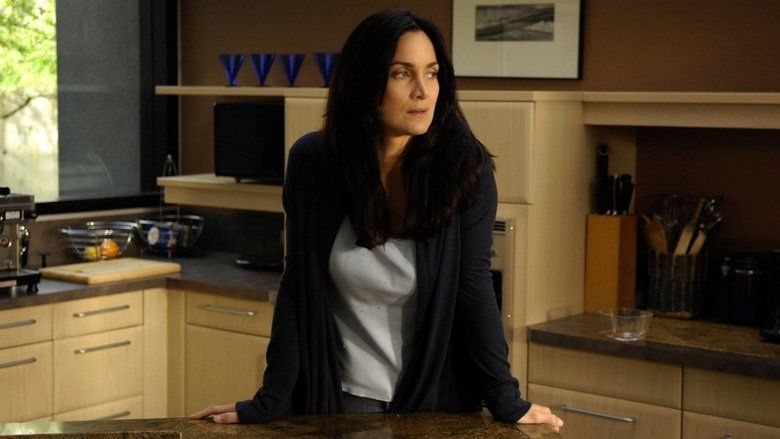 Carrie-Anne Moss looking afar while wearing a black blazer and gray inner blouse in a movie scene from the 2007 film, Normal