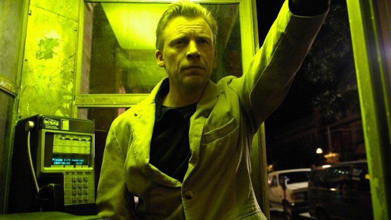 Callum Keith Rennie standing beside the payphone while wearing a coat and shirt in a movie scene from the 2007 film, Normal
