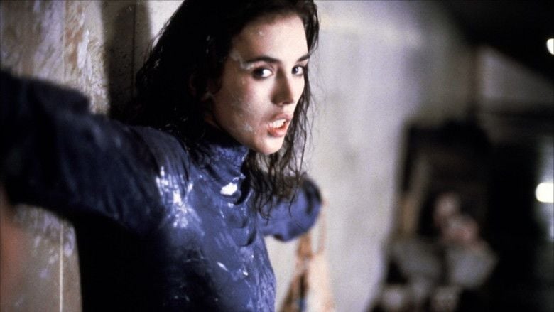 Isabelle Adjani hanging on a wall while wearing a blue long sleeve blouse in a movie scene from the 1981 film, Possession