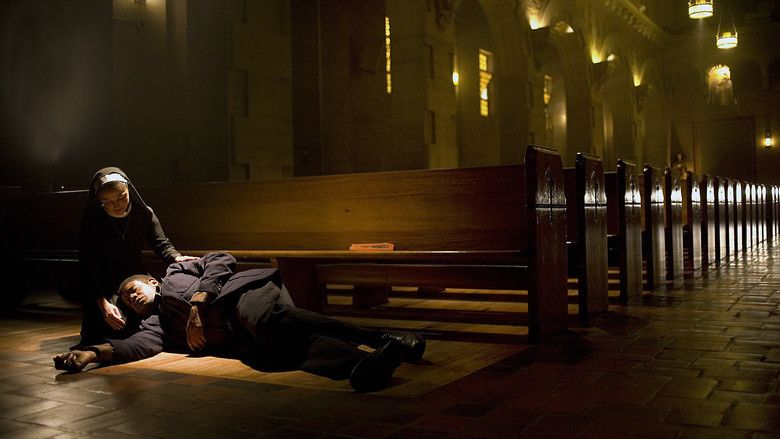 Forest Whitaker lying on the floor of the church and his head is on Soledad Campos' lap. Forest is wearing a black coat, black pants, and black shoes while Soledad is wearing a black and white religious habit in a scene from the 2008 drama film, Powder Blue