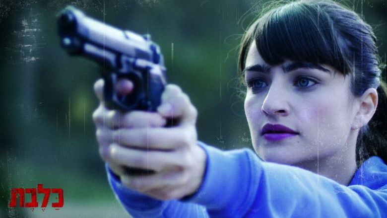 Ania Bukstein holding a gun while wearing a blue jacket in a scene from the 2010 Israeli film, Rabies