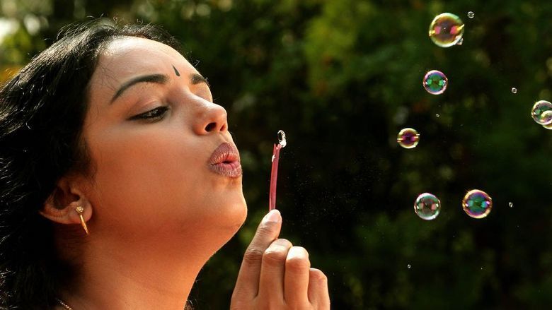 Shweta Menon playing bubbles in a movie scene from the 2011 erotic drama film Rathinirvedam