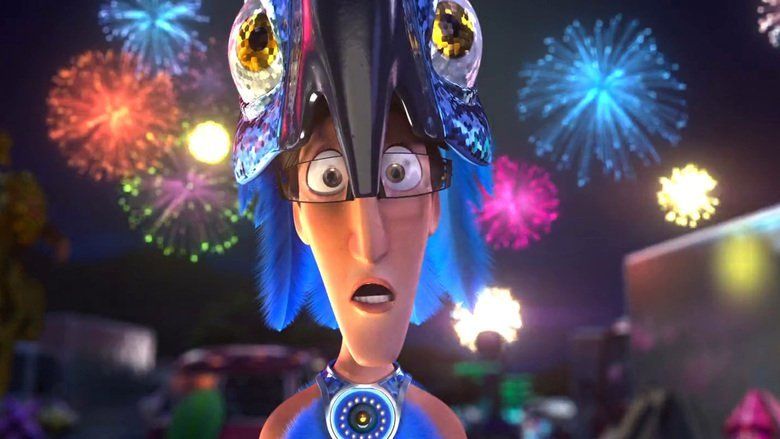 In the movie scene of Rio 2011, Tulio is surprised, mouth half open standing in the middle with fireworks at the back, has brown hair, brown eyes, wearing a spix’s macaw costume on top of his head, black eyeglasses a and blue costume with round pendant on his neck.