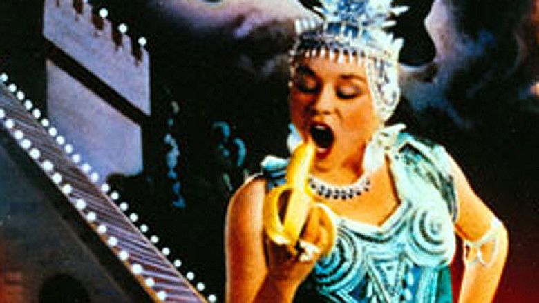 Imogen Millais-Scott eating a banana while wearing a blue headdress and blue bodysuit in the 1988 British film, Salome's Last Dance