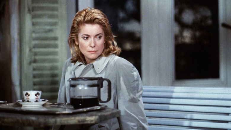 Catherine Deneuve as Lili with a serious face and blonde hair in a movie scene from Scene of the Crime (1986 film).