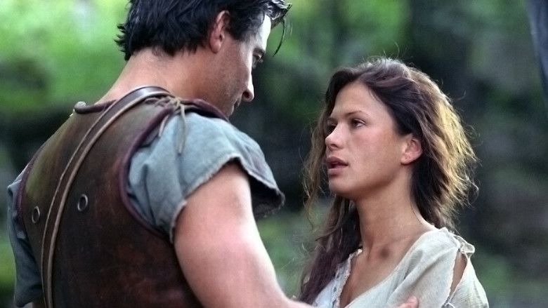 Goran Visnjic and Rhona Mitra with serious faces while talking to each other. Goran is wearing a brown vest over a gray shirt while Rhona is wearing a ripped white shirt in a movie scene from Spartacus, 2004 North American miniseries.