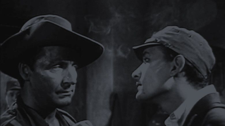 Reed De Rouen as Michael Brodie with a serious face in front of a man and wearing a hat in a movie scene from The Hand, a 1960 British horror film.