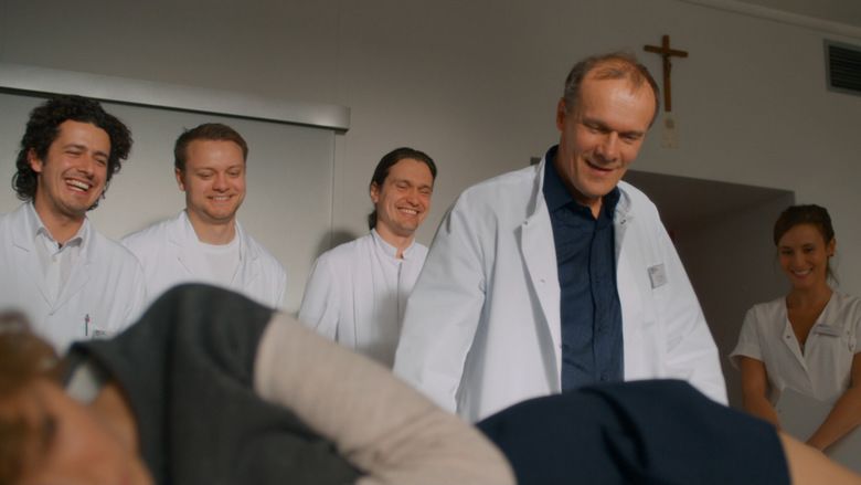 Carla Juri lying on the bed while Edgar Selge together with other nurses are looking at her butt in a scene from the 2013 film, Wetlands