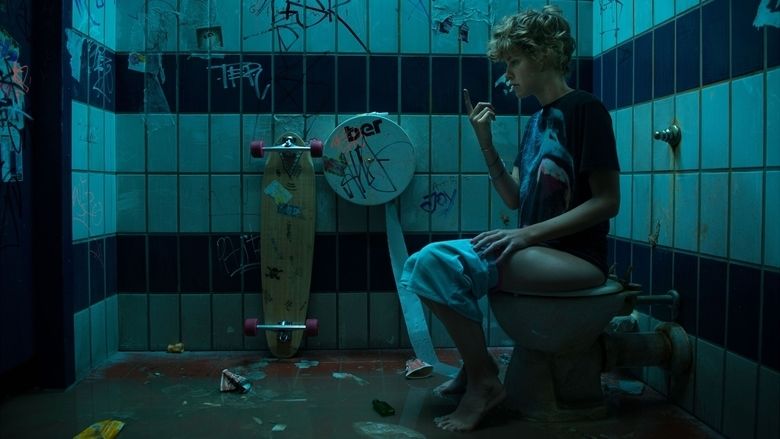 Carla Juri sitting on a toilet bowl while looking at her finger in a scene from the 2013 German drama film, Wetlands