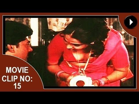 Movie clip no. 15 of Aadhi Thaalam, a 1990 Indian Malayalam film starring Jayarekha bending down while looking at a man, wearing a necklace, and a pink Indian dress.