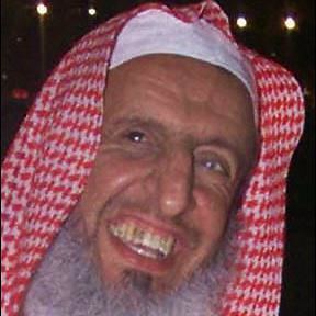 Abd al-Aziz ibn Baz smiling with a thick white beard and wearing a red and white kufiyah.