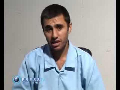 Abdolmalek Rigi speaking in an interview being shown in a TV show wearing blue prison clothing.