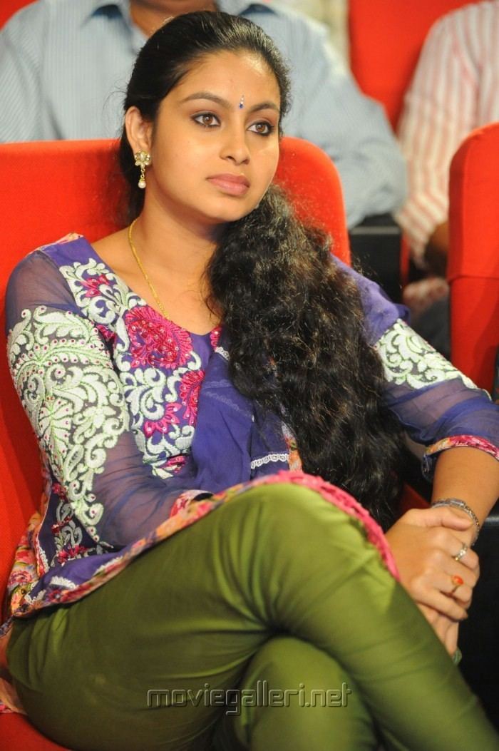 Abhinaya in fierce look while sitting on a chair wearing earrings, necklace, sleeve, and green pants