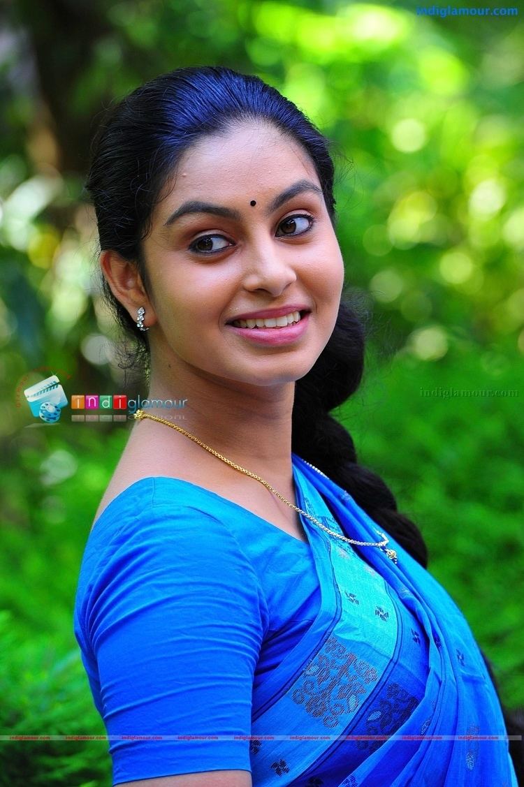 Abhinaya smiles while wearing earrings, a necklace, and a dress outdoor