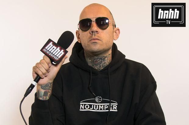 Adam Grandmaison is serious, holding a microphone, with a tattoo on his neck and arm, wearing sunglasses and a black jacket, at the top right A black box with white border with a word HNHH TV