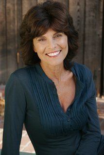 Adrienne Barbeau smiling, with short hair, and wearing a dark green long sleeve blouse.