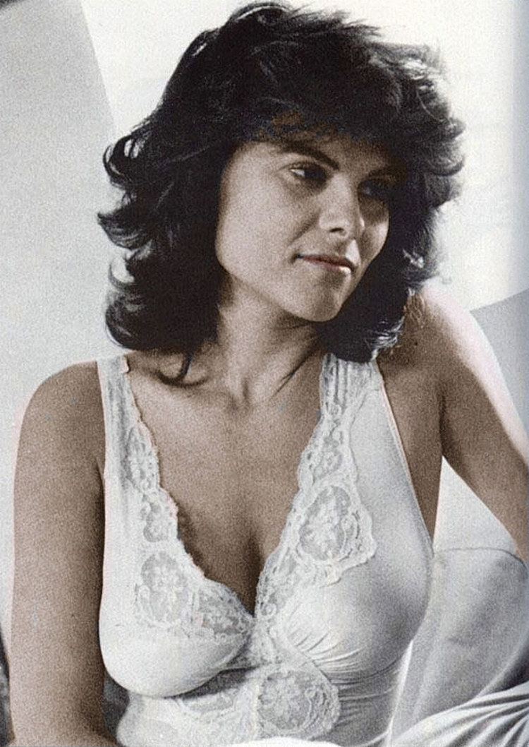 Adrienne Barbeau smiling, with messy-look short hair, and wearing white lingerie.