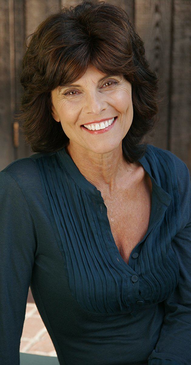 Adrienne Barbeau smiling, with short hair, and wearing a dark green long sleeve blouse.
