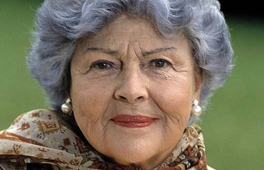 Aenne Burda smiling closed mouth with short gray hair and wearing a light brown scarf.