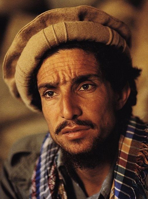 Ahmad Shah Massoud wearing a brown desert hat and a multicolored scarf with facial hair.