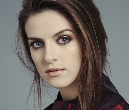 Aisling Loftus is serious, has brown hair, wearing a red-black top.