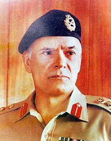 Akhtar Abdur Rahman looking at the right side with a serious face while wearing a black beret cap and brown polo with insignia and badges