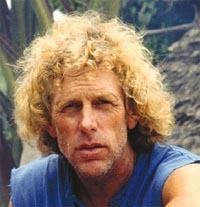 Alby Mangels with a furrowed forehead and blonde curly hair while wearing a blue shirt