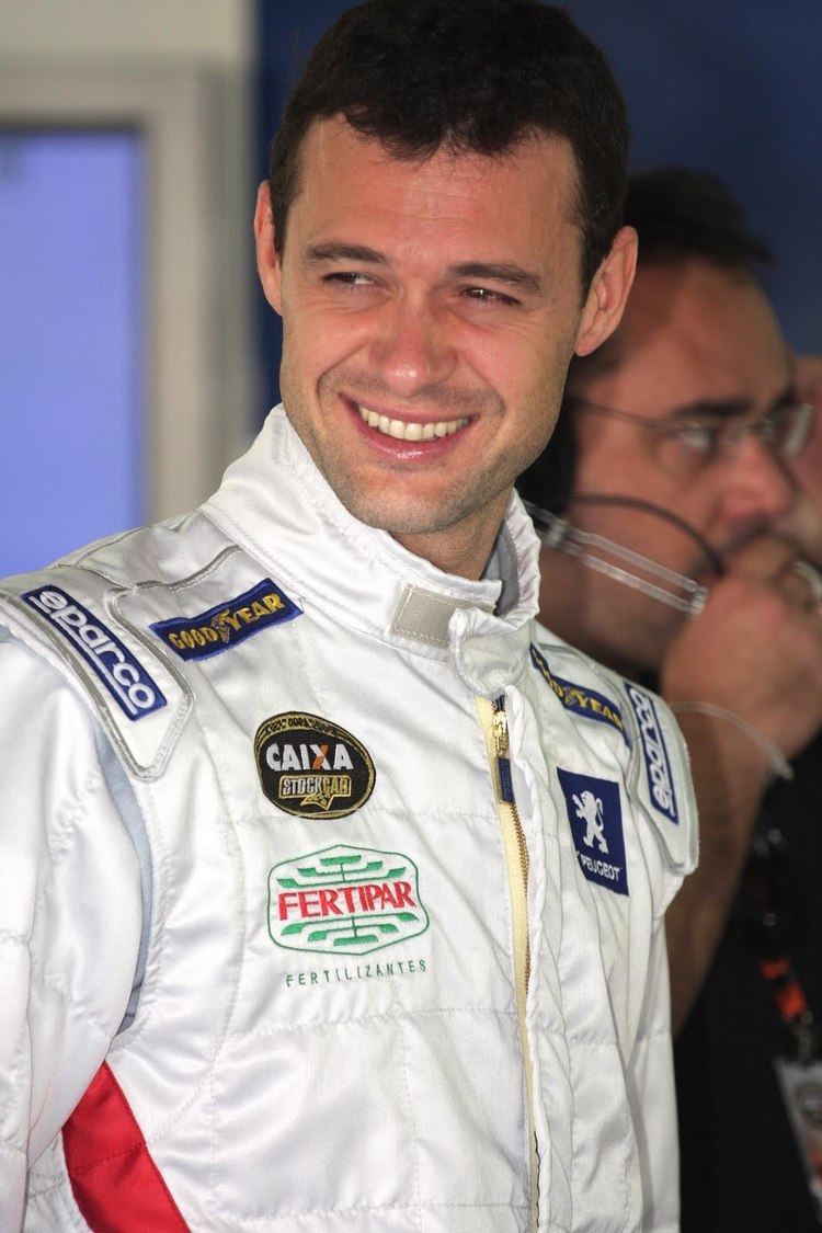 Alceu Feldmann smiling while looking afar and wearing a white racing suit
