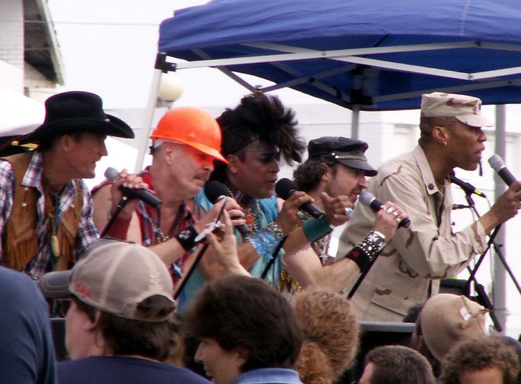 Alex Briley at the right with the Village People singing at Asbury Park, New Jersey while wearing a beige cap and beige long sleeves