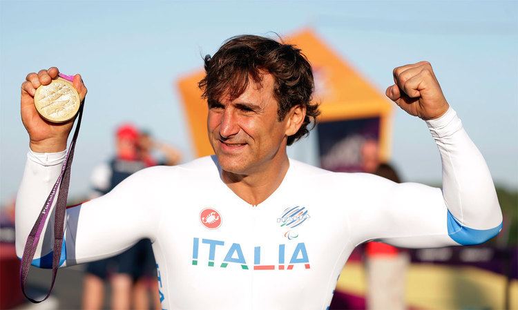 Alex Zanardi smiling while proudly showing his medal