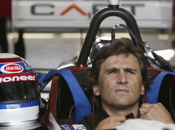 Alex Zanardi looking afar while sitting on his car